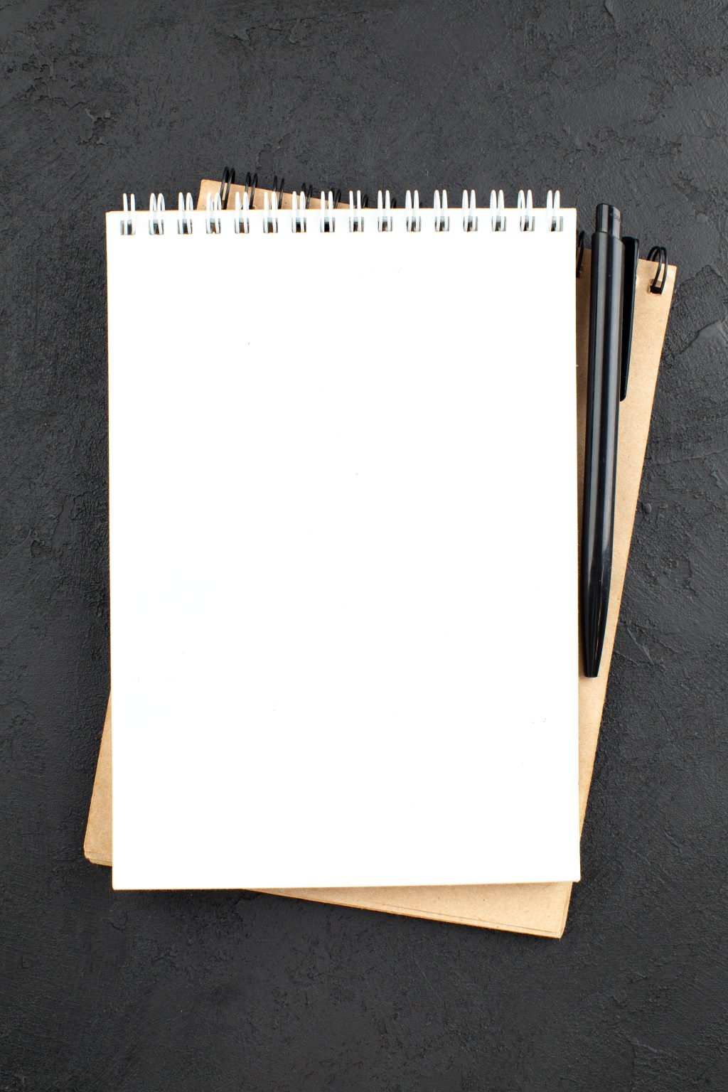 top-view-spiral-notepad-black-pen-black-table