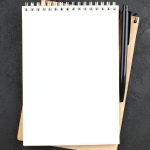 top-view-spiral-notepad-black-pen-black-table